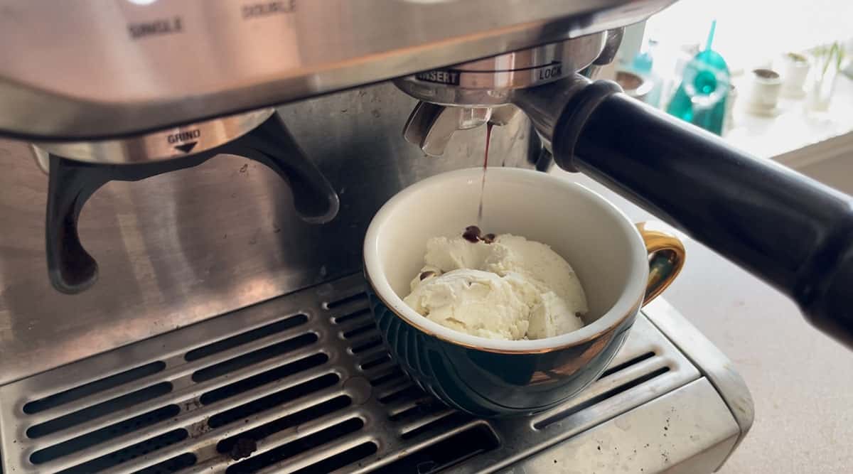 An espresso shot being pulled onto a cappuccino cup containing vanilla ice cream