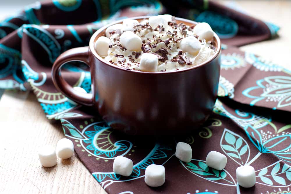 A mug of hot cocoa with whipped cream, marshmallows, and chocolate shavings
